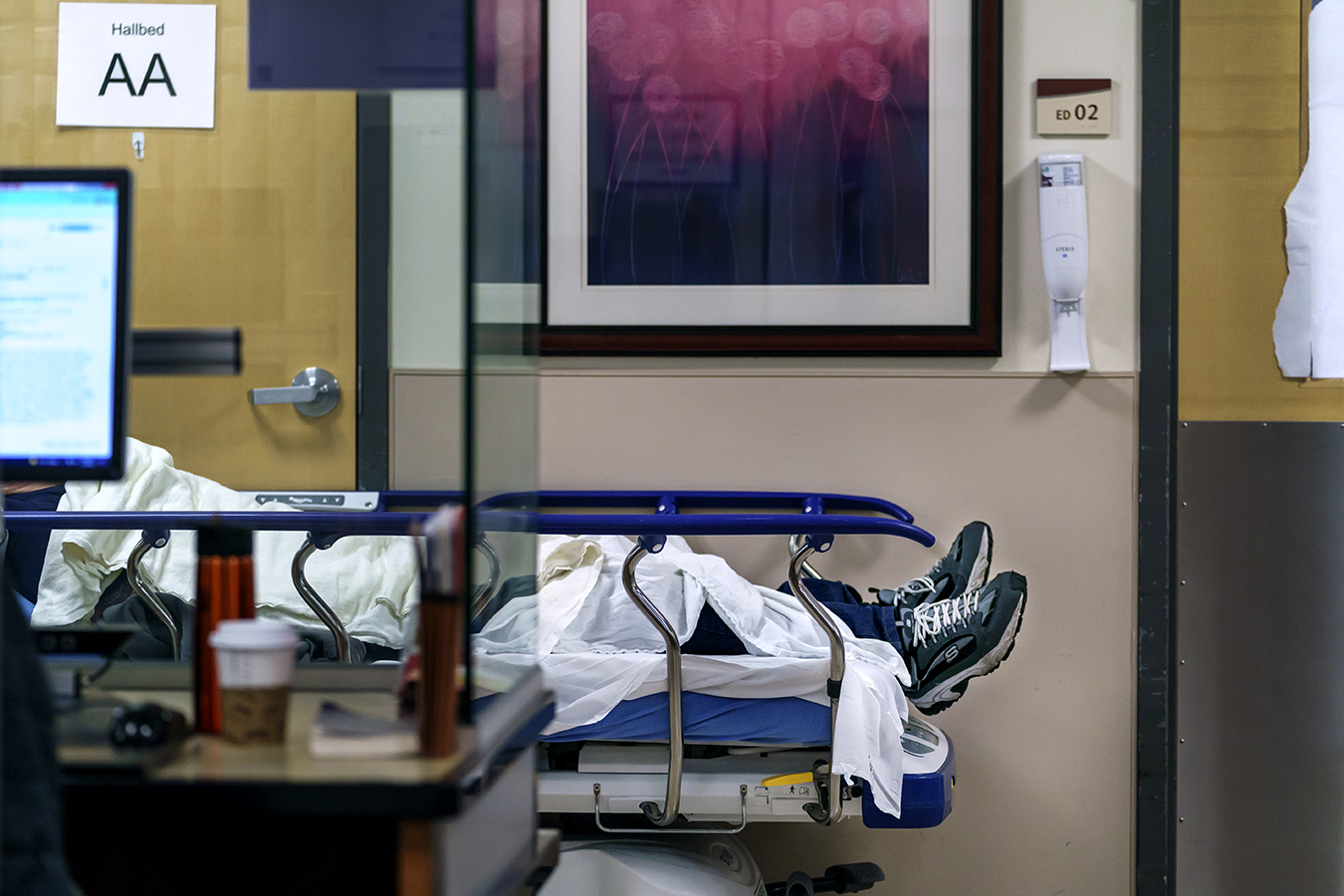 Non-identifiable patient lies in a gurney in a hospital hallway