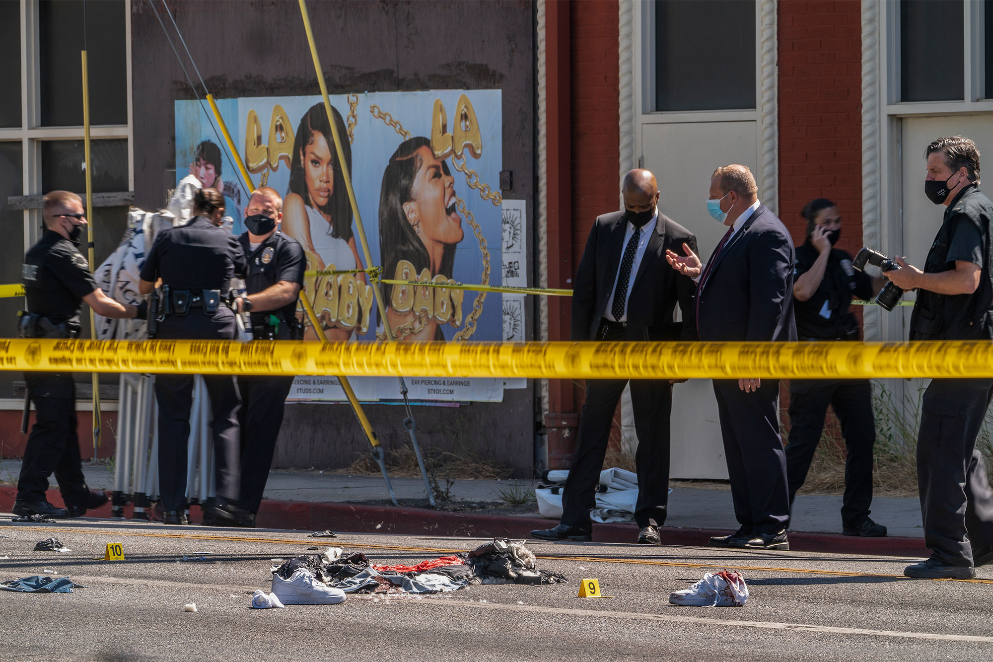 A photographer with the Los Angeles Police Department, far right, documents the remains of a crime scene in Beverly Hill, Calif., Friday, June 25, 2021.