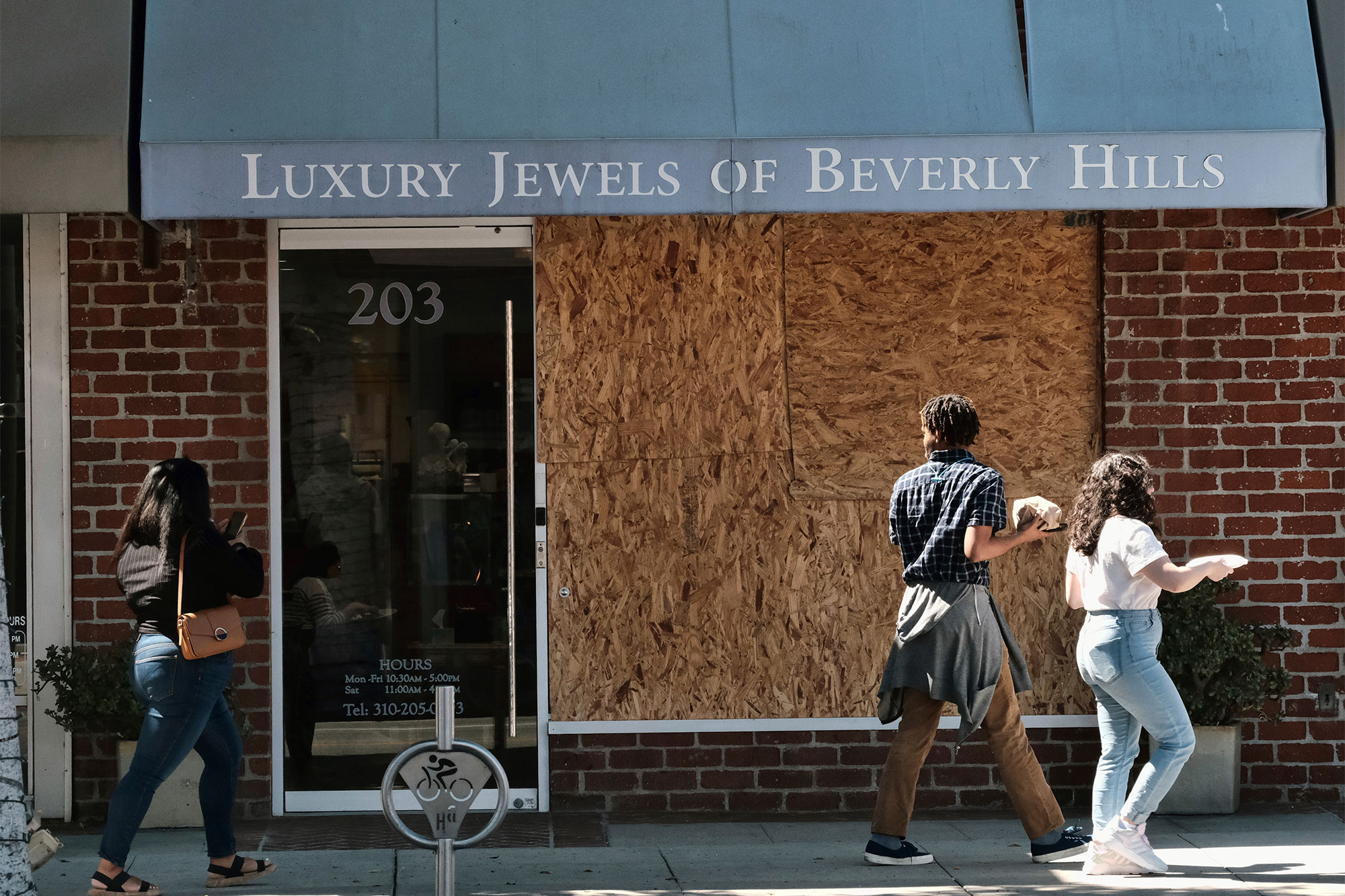 Pedestrians walk past a boarded up Luxury Jewels of Beverly Hills on Wednesday, March 23, 2022 in Beverly Hills, Calif. 