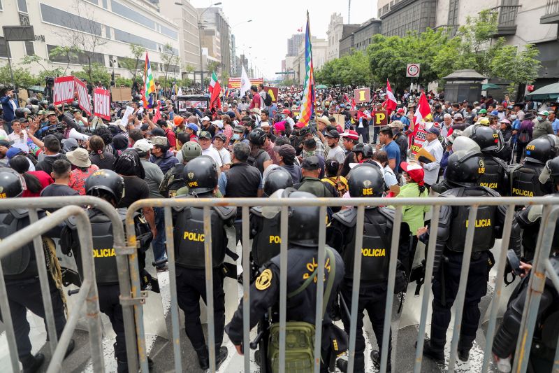 Police officers stand guard as people gather outside Peru's Congress after President Pedro Castillo said he will dissolve it on December 7.